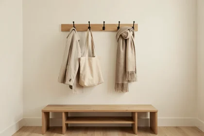 Porte-manteaux mural moderne en bois et métal noir installé dans un studio aux murs blancs avec parquet clair
