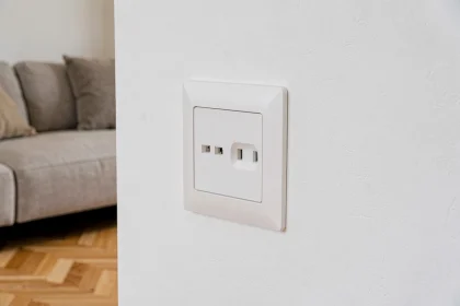 Prise double Legrand encastrée dans un mur blanc d'un salon contemporain avec parquet en chêne