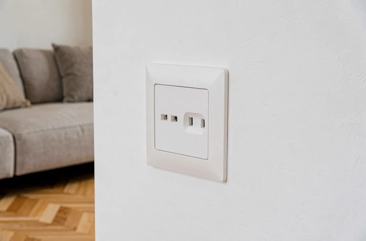 Prise double Legrand encastrée dans un mur blanc d'un salon contemporain avec parquet en chêne