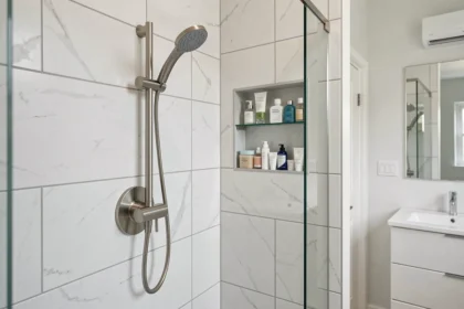 Système de douche à effet pluie Hudson Reed en finition nickel brossé installé dans une salle de bains moderne avec carrelage blanc grand format
